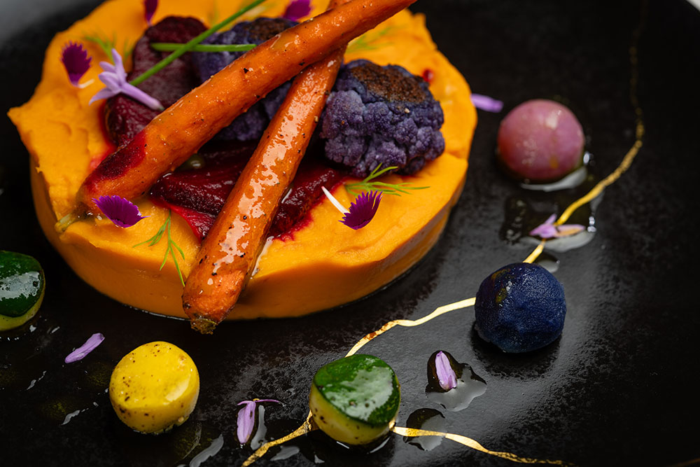 Carrot and beetroot purée with roasted heirloom vegetables and edible blossoms.