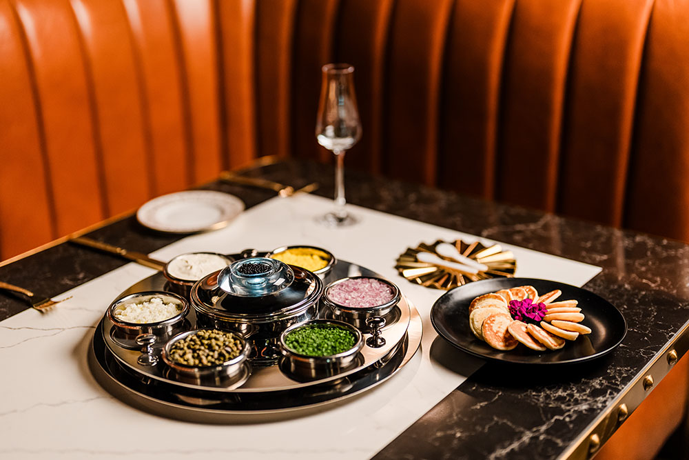 Signature caviar with blinis, crème fraîche, and traditional accompaniments.